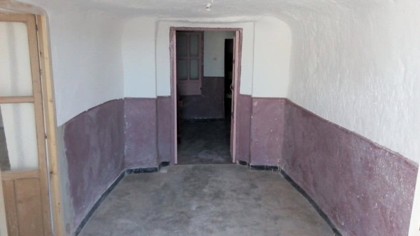 Interior view of a traditional cave house in Freila, Granada, showcasing rustic walls and doorway.