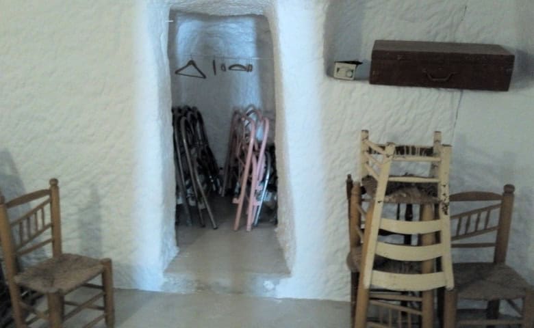 Charming cave house interior in Freila, Granada, featuring rustic furniture and unique architecture.