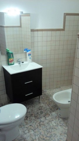 Charming cave house bathroom in Freila, Granada, featuring a modern sink, toilet, and tiled walls. P.