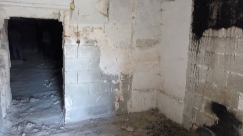Interior view of a rustic cave house in La Alqueria, Granada, showcasing unfinished stone walls.