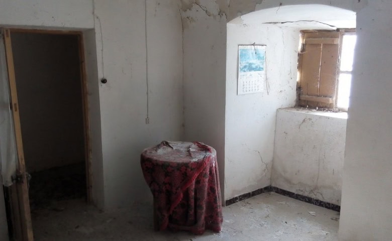 Interior view of a rustic cave house in La Alqueria, Granada, showcasing simple walls and natural li.