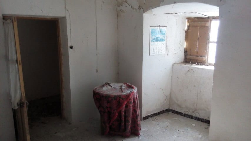 Interior view of a rustic cave house in La Alqueria, Granada, showcasing simple walls and natural li.
