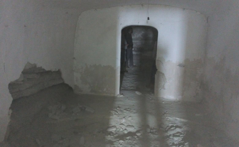 Interior view of a cave house in La Alqueria, Granada, showing smooth white walls and an arched door.