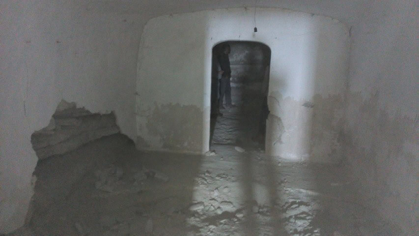 Interior view of a cave house in La Alqueria, Granada, showing smooth white walls and an arched door.