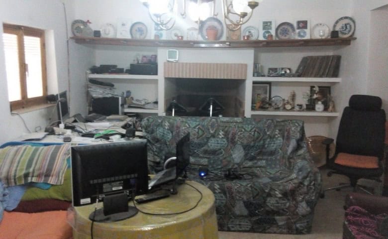 Cozy living room with a sofa, shelves, and a fireplace in a traditional Cave House in Pulpite, Grana.