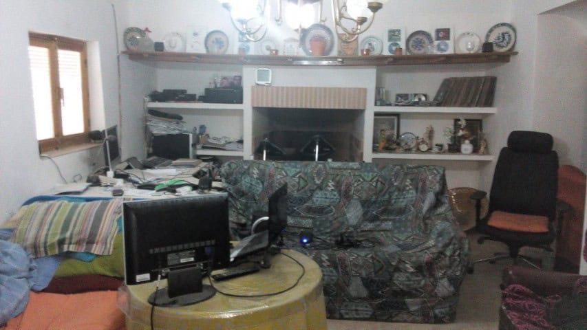 Cozy living room with a sofa, shelves, and a fireplace in a traditional Cave House in Pulpite, Grana.