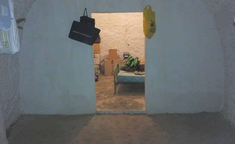 Interior view of a rustic cave house in Pulpite, Granada with simple furnishings and storage items.