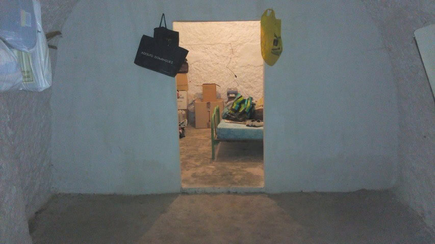 Interior view of a rustic cave house in Pulpite, Granada with simple furnishings and storage items.