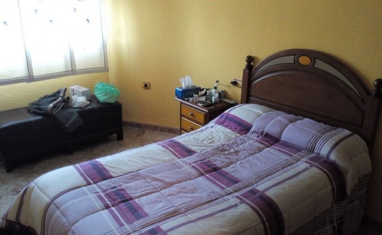 Bedroom with double bed and wooden headboard in Baza, Granada.