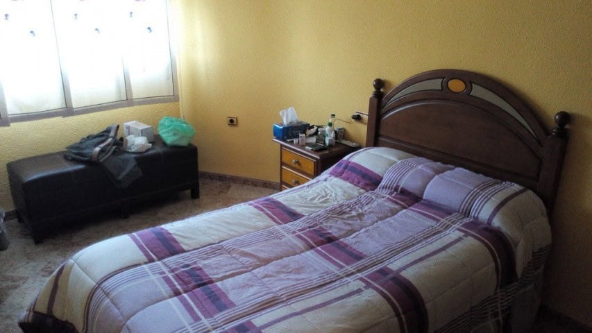 Bedroom with double bed and wooden headboard in Baza, Granada.