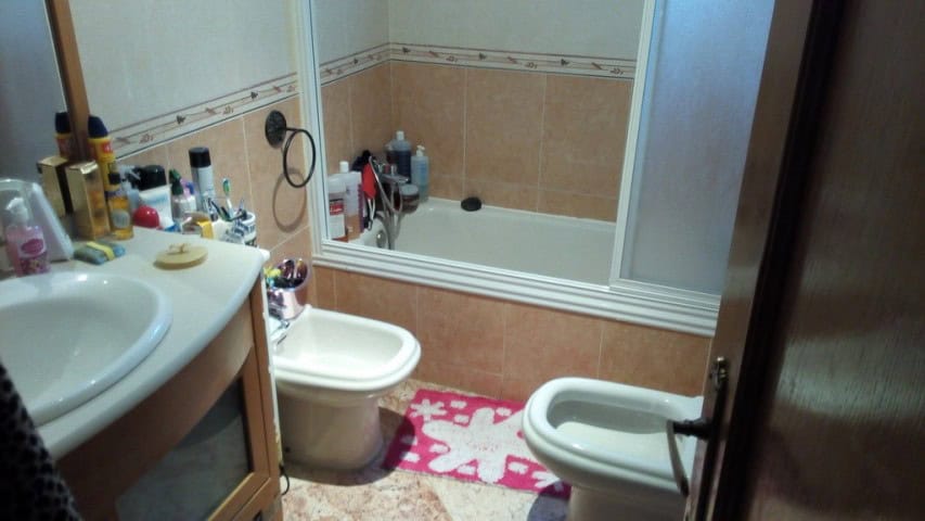 Bathroom with bathtub, sink, and bidet in Baza, Granada, featuring neutral tiles and personal care i.