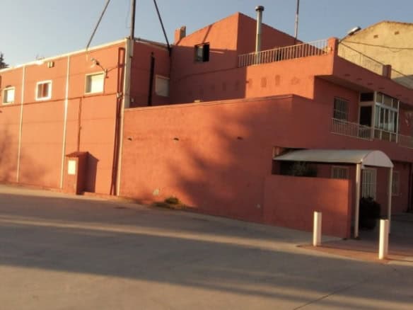 Commercial property for sale in Baza, Granada, featuring a modern building with vibrant red exterior.