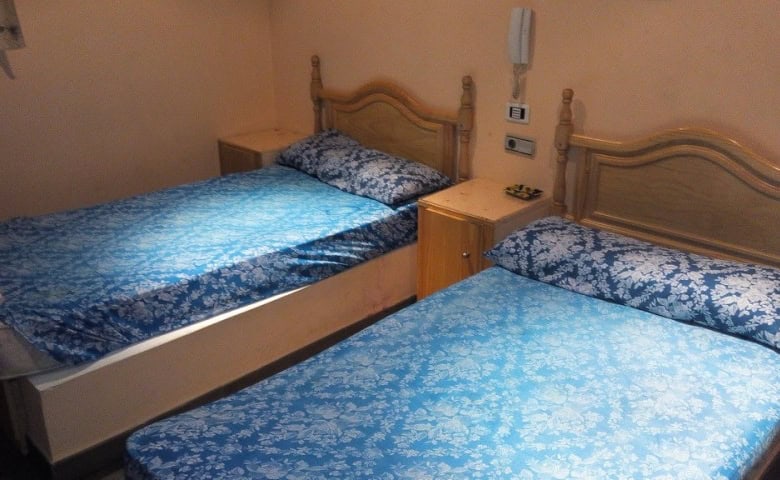 Twin beds in a hotel room in Baza, Granada, with wooden headboards and blue patterned bedding.