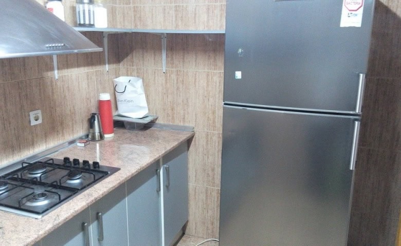 Modern commercial kitchen with stove, refrigerator, and countertop in Baza, Granada.
