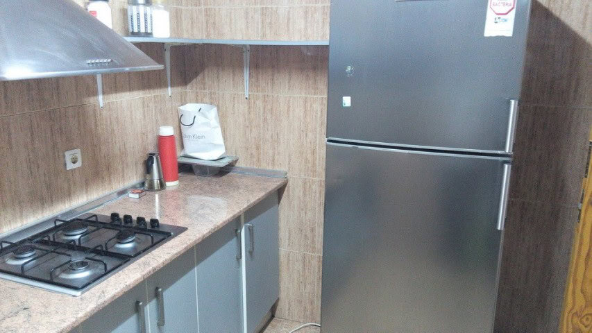 Modern commercial kitchen with stove, refrigerator, and countertop in Baza, Granada.