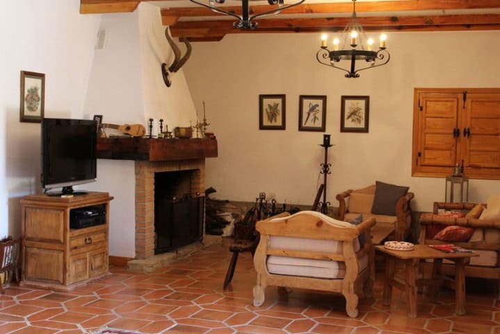 Charming interior of a rustic finca in Larva, Jaen, featuring traditional wooden beams, cozy seating.