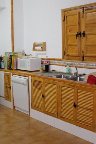 Rustic kitchen with wooden cabinets and modern appliances in Finca Larva, Jaen.