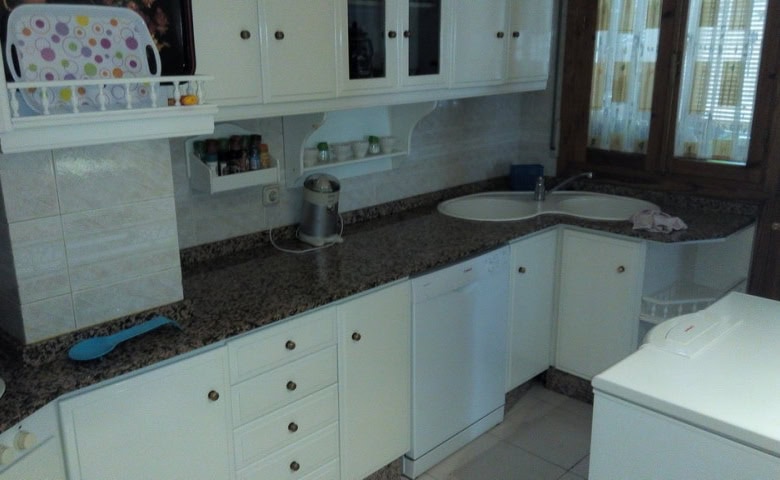 Bright kitchen in an apartment located in Baza, Granada, featuring white cabinets and modern applian.