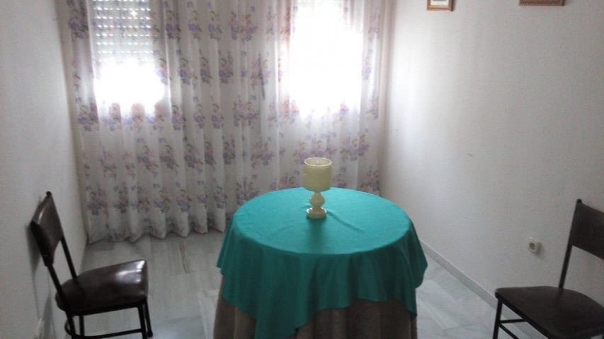 Bright interior of a small apartment in Baza, Granada, with a round table and two chairs near a wind.