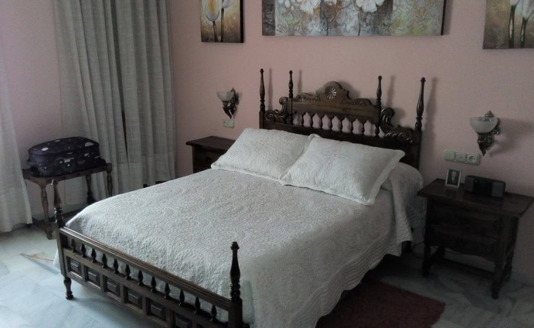 Comfortable bedroom in Baza, Granada featuring a traditional wooden bed and stylish decor.