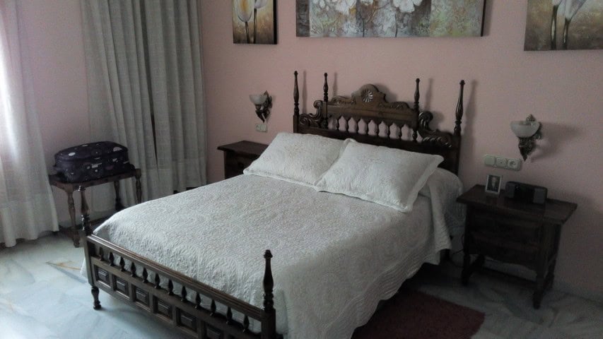 Comfortable bedroom in Baza, Granada featuring a traditional wooden bed and stylish decor.