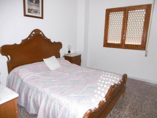 Cozy bedroom with wooden furniture and natural light in a village property in Cuenca, Jaen.