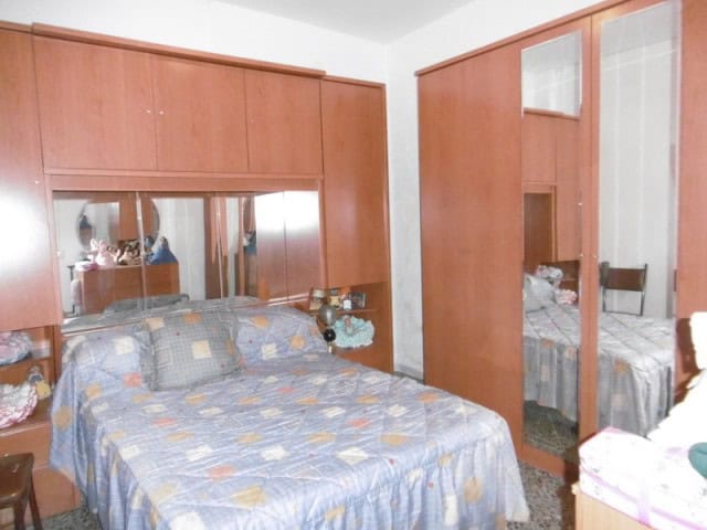 Spacious bedroom with wooden furniture and mirror in a village property in Cuenca, Jaen.