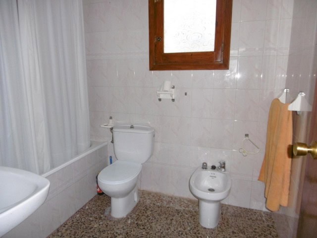 Charming bathroom in a village property in Cuenca, Jaen with white tiles and wooden window.