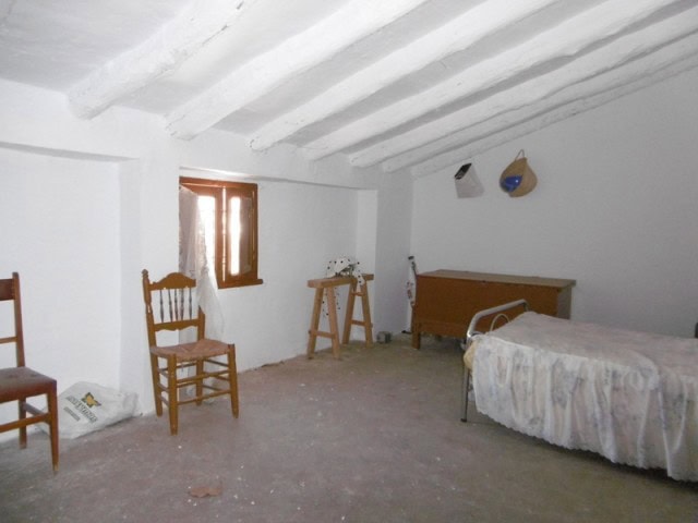 Charming rural bedroom in Belerda, Jaen with rustic wooden furniture and whitewashed walls.