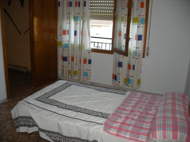 Cozy bedroom with colorful curtains and a view from the window in Cuevas del Campo, Granada.