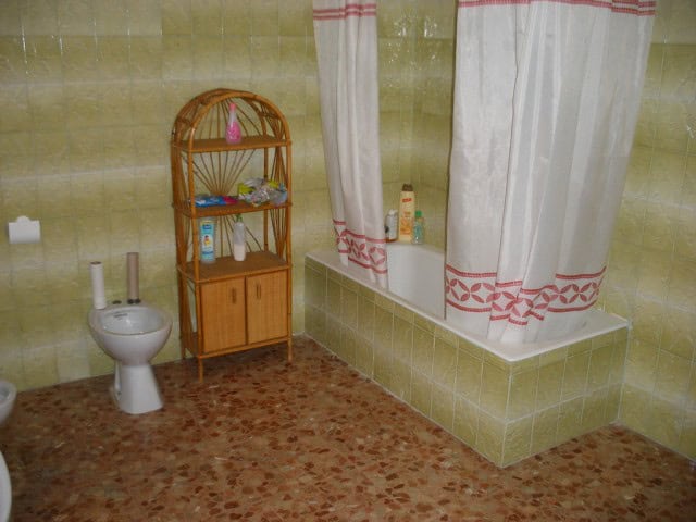 Cozy bathroom with bathtub, shower curtain, and toilet in a traditional Spanish apartment.