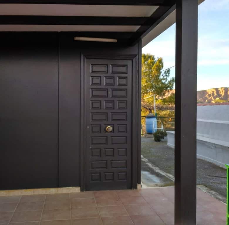 Log home entrance with black door and porch in Freila, Granada, Spain.