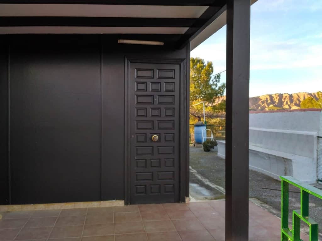 Log home entrance with black door and porch in Freila, Granada, Spain.