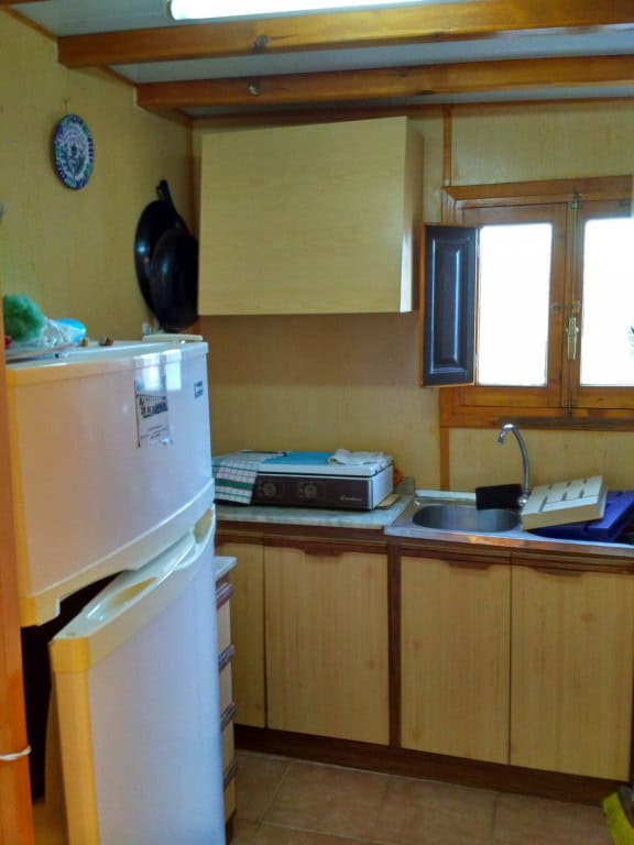Interior view of a rustic log home kitchen in Freila, Granada with wooden cabinets and a small windo.