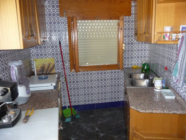 Charming kitchen in a town house in Baza, Granada, featuring wooden cabinets and modern appliances.