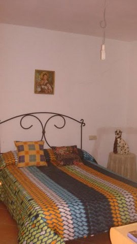 Interior of a rural bedroom with colorful bedspread and decorative dog figure.