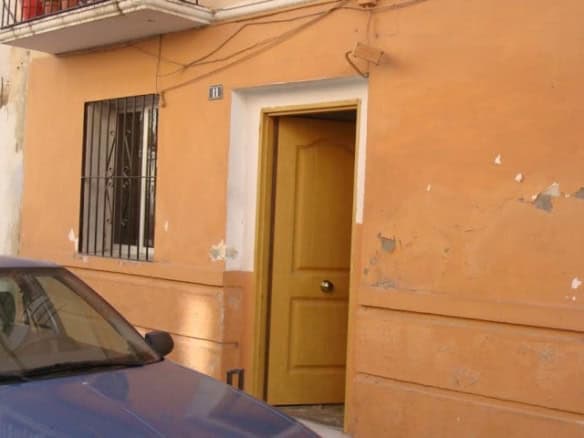 Cozy apartment entrance in Baza, Granada with a yellow door and rustic exterior.