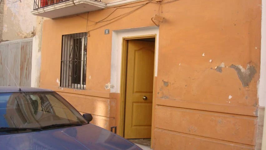 Cozy apartment entrance in Baza, Granada with a yellow door and rustic exterior.