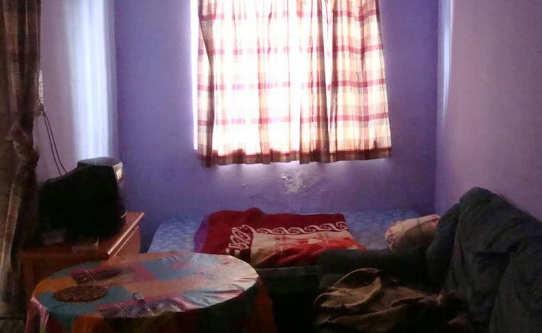Interior view of a small apartment in Baza, Granada, featuring a bed, sofa, and window with curtains.