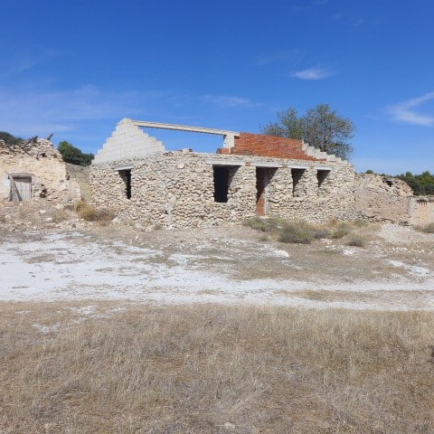 Ancient stone ruin in Cullar, Granada, with partially restored structure under a clear blue sky.