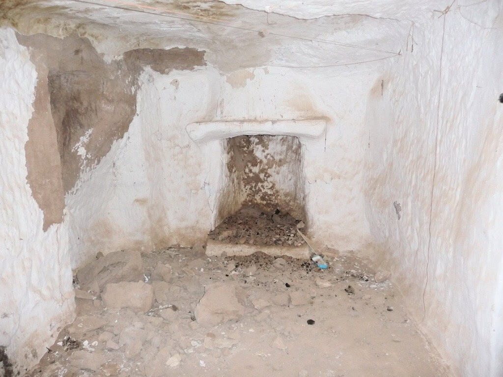Cave house interior in Freila, Granada, showing rustic stone walls and a small fireplace.