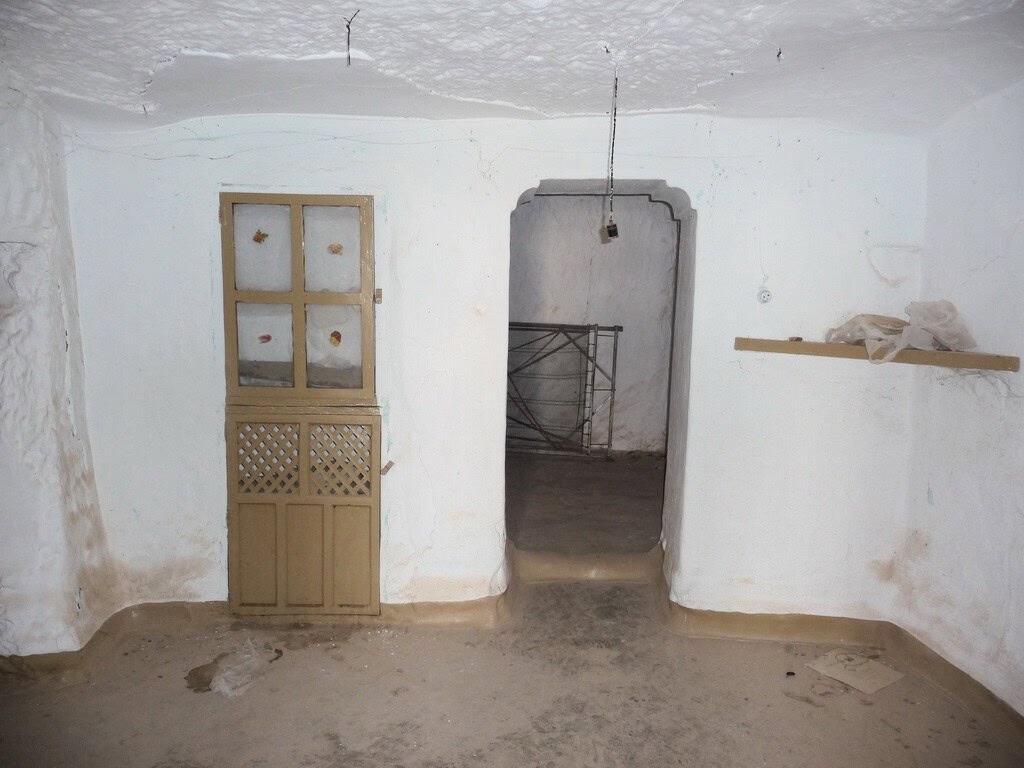 Cave house interior with whitewashed walls and rustic wooden door in Freila, Granada. Unique living.