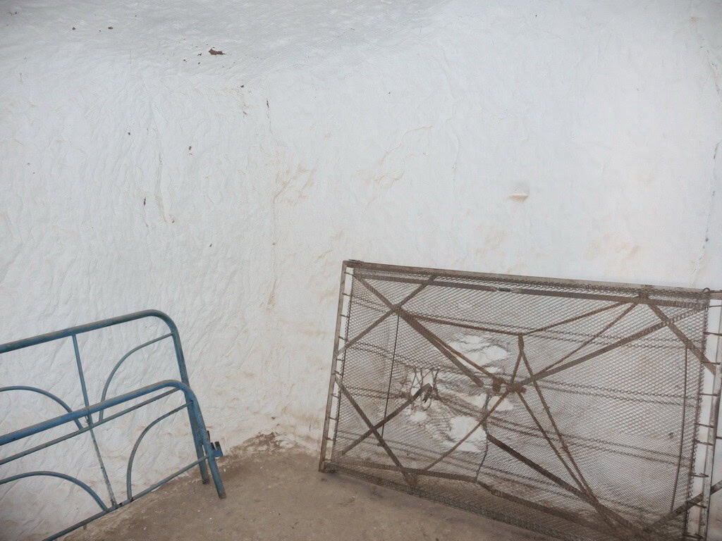 Cave house exterior in Freila, Granada with metal bed frame and rustic white wall.