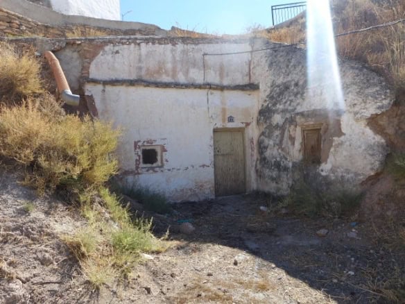 Cave house exterior in Freila, Granada, with rustic door and small window. Unique property in a scen.