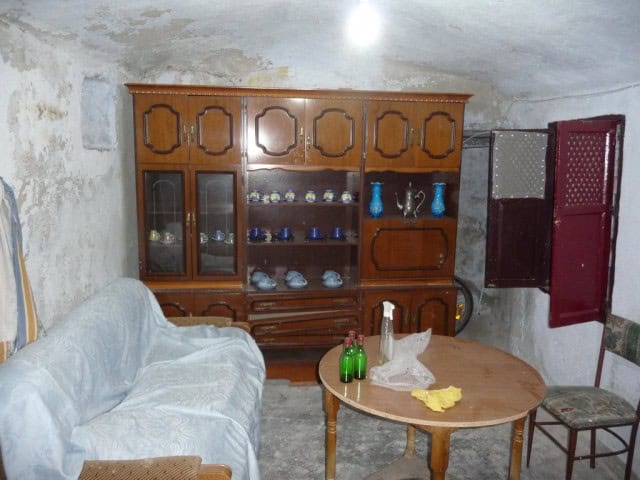 Cave house interior in Freila, Granada, featuring rustic furniture and unique stone walls.