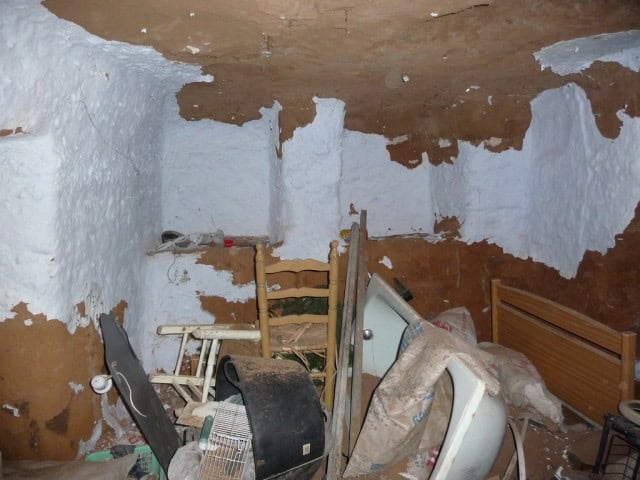 Unique cave house interior in Freila, Granada, showing rustic walls and basic furnishings.