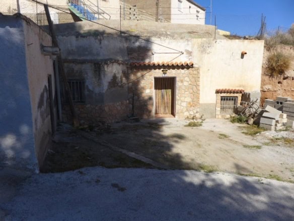 Cave house in Freila, Granada, with rustic stone walls and a small wooden door.