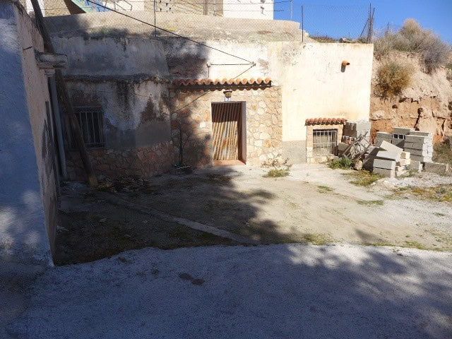 Traditional cave house in Freila, Granada, with rustic stone walls and a wooden door.