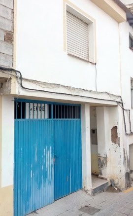 Traditional village house in Zujar with a blue garage door in Granada, Spain.