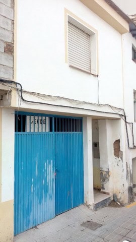 Traditional village house in Zujar with a blue garage door in Granada, Spain.